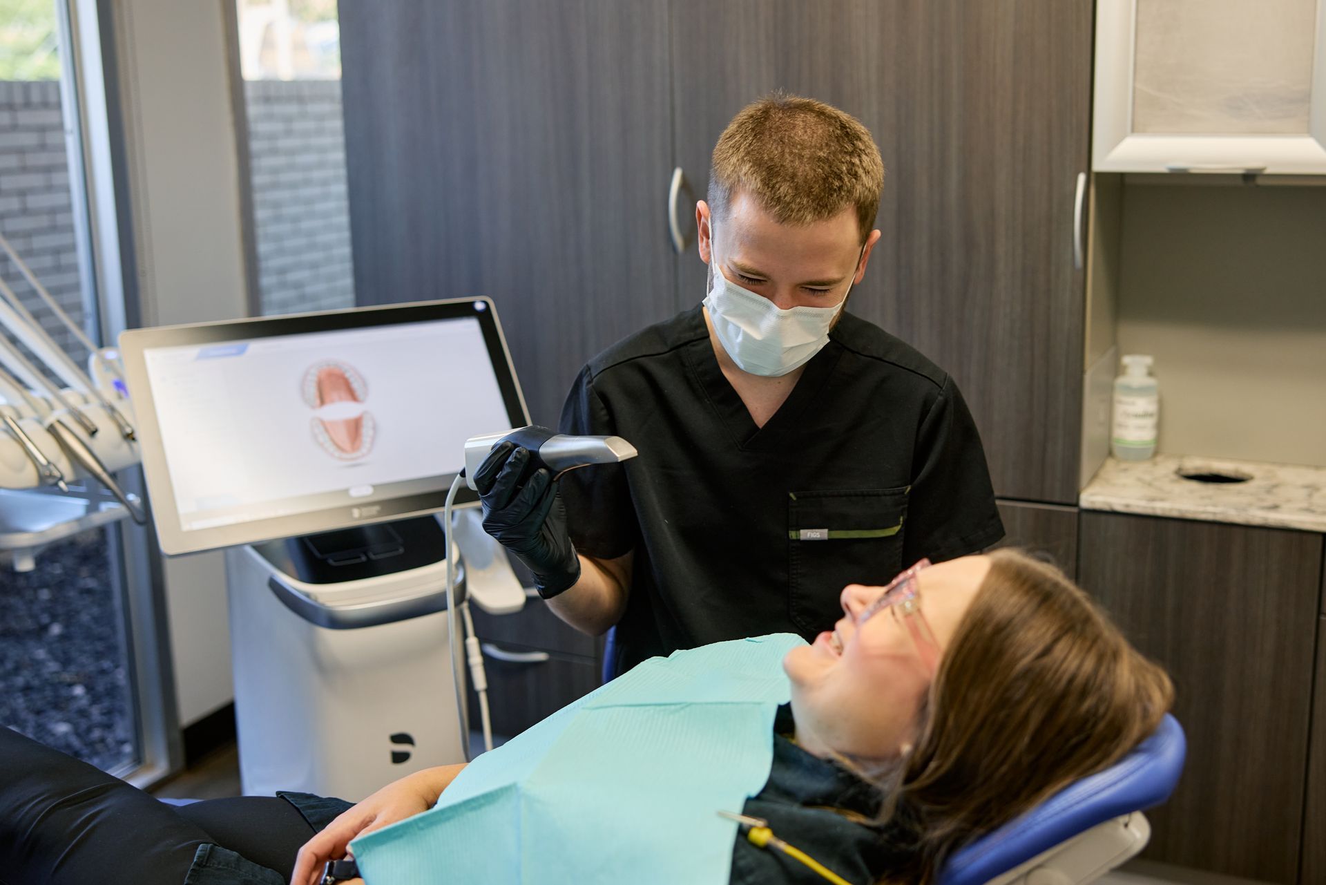 Dentist scanning a patient's mouth with a digital scanner in a dental office.