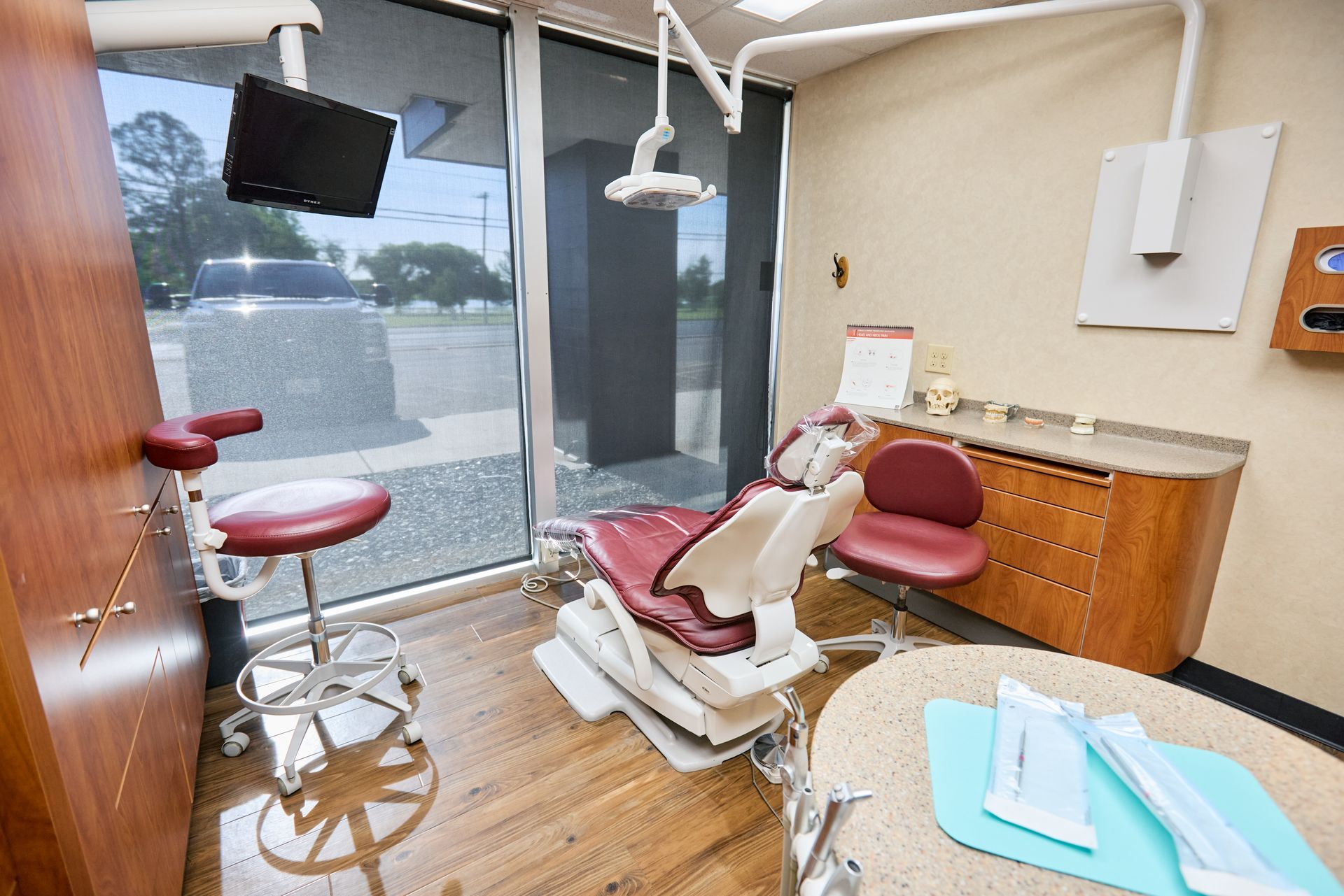Dental operatory with red chair, window, and equipment.