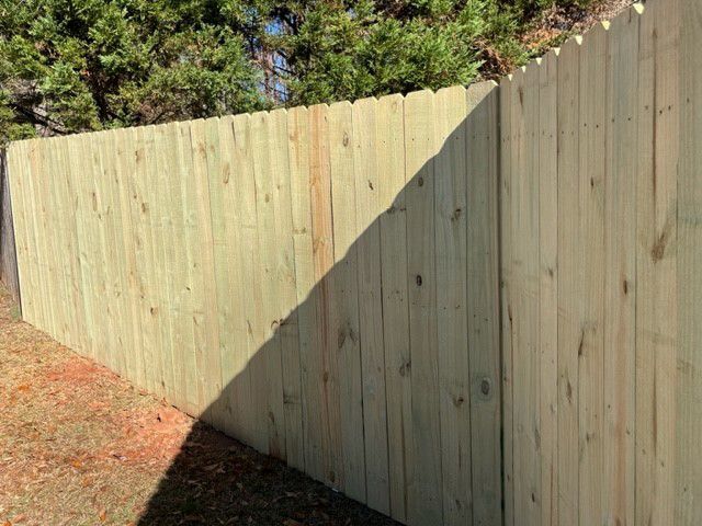 a wooden fence with a tree in the background and a shadow on it .