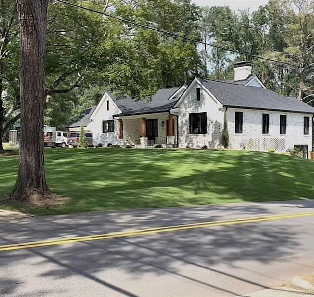 a white house with a black roof sits on a lush green hillside