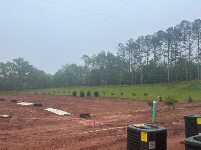 a large dirt field with a lot of trees in the background .