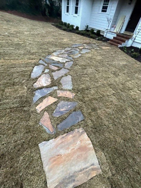 a stone walkway leading to a house in the grass .