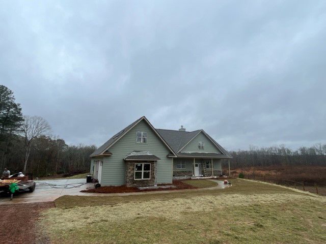 a house is sitting on top of a grassy hill in the middle of a field .