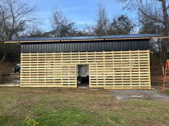 a shed is being built with wooden pallets and a metal roof .