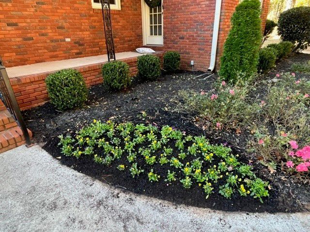 a garden with flowers and bushes in front of a brick house .