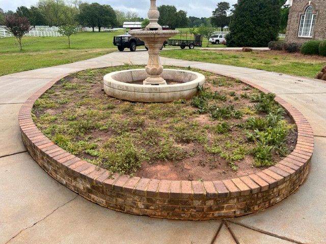 there is a fountain in the middle of a brick planter .