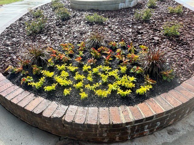 a brick planter filled with flowers and mulch .