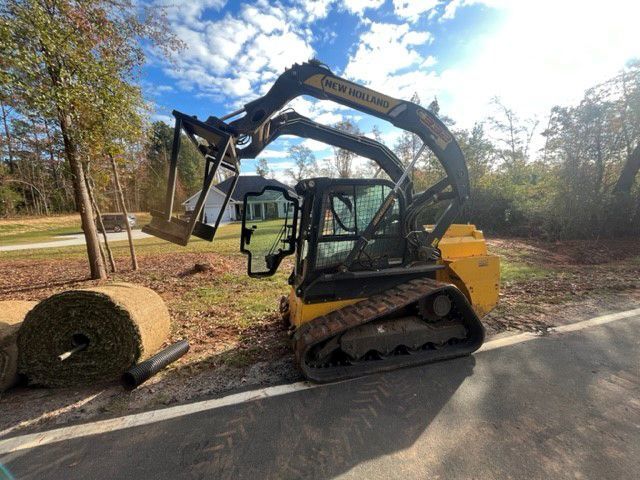 a bulldozer is sitting on the side of the road next to a bale of hay .