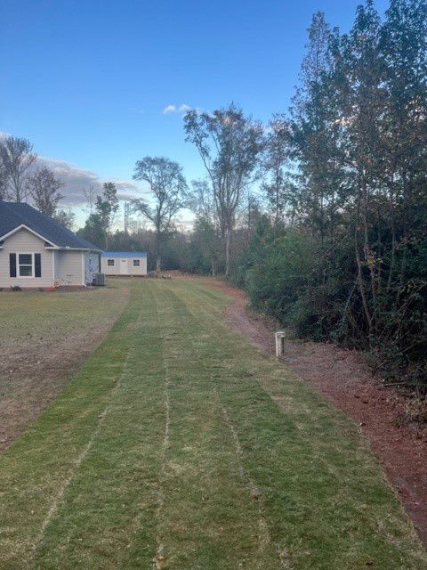 there is a house in the background and a lush green field in the foreground .