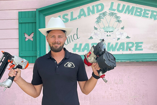 Man in a cowboy hat holds nail guns in front of