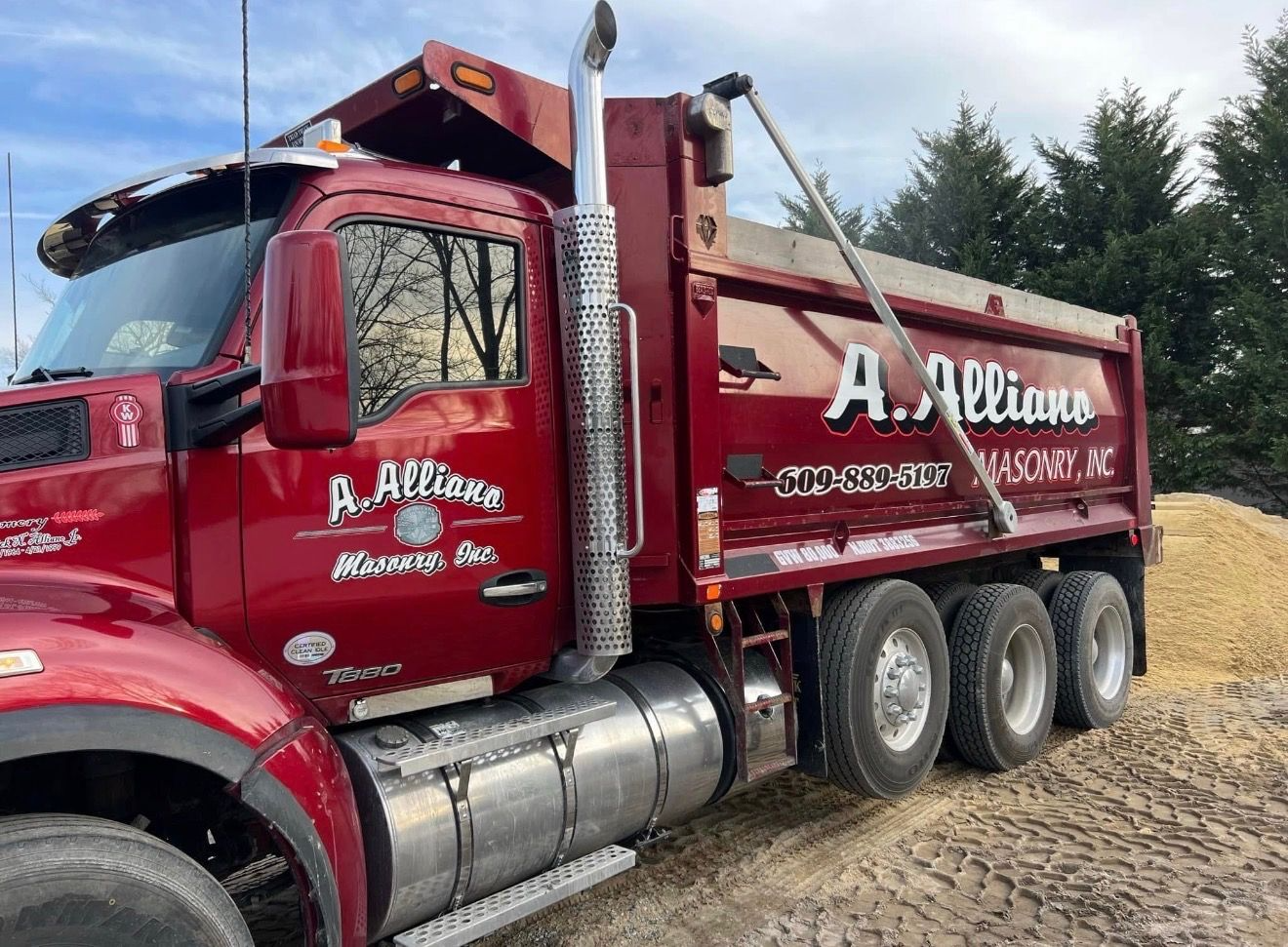 Red A. Allians dump truck on a sandy ground.
