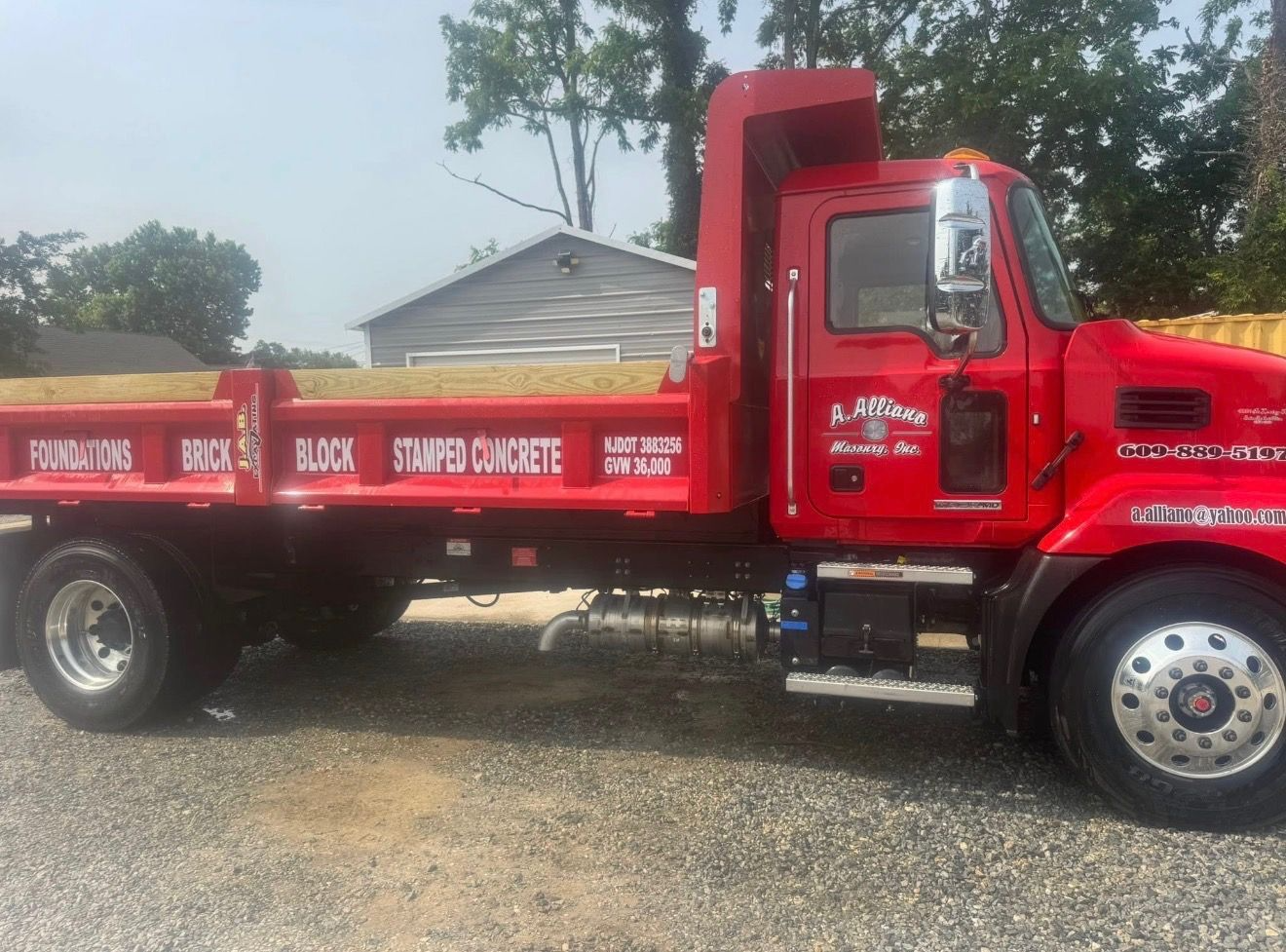 Red dump truck parked on gravel, with text 