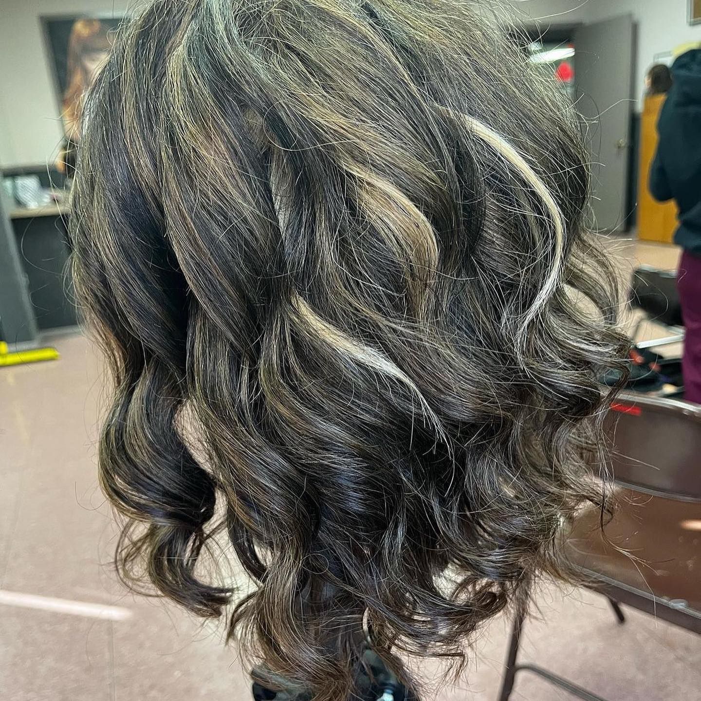 Wavy dark hair with blonde highlights on a mannequin head, indoors.