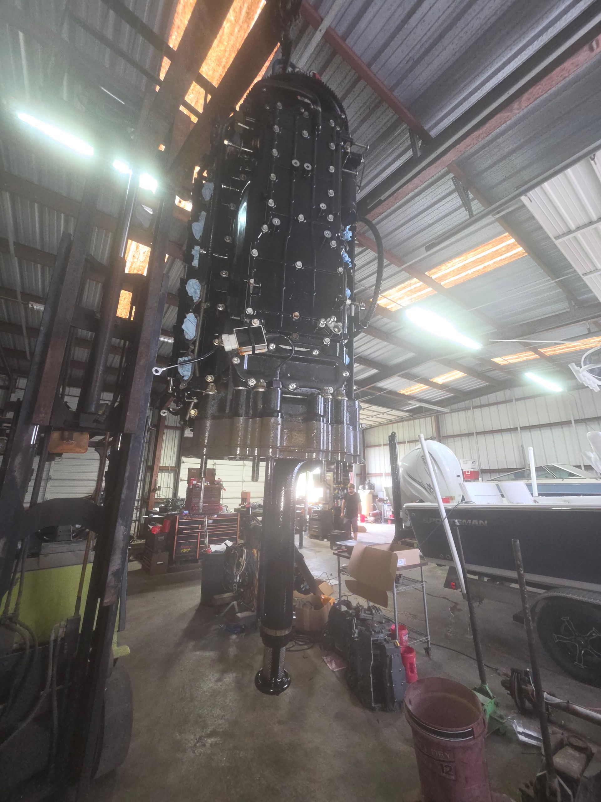 Black tower-like structure inside a warehouse, surrounded by equipment and bright overhead lights.