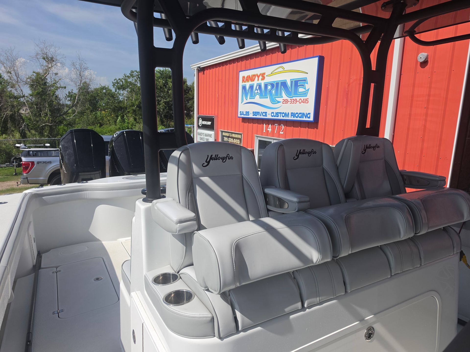 White boat seating with canopy beside a red building and marina sign.