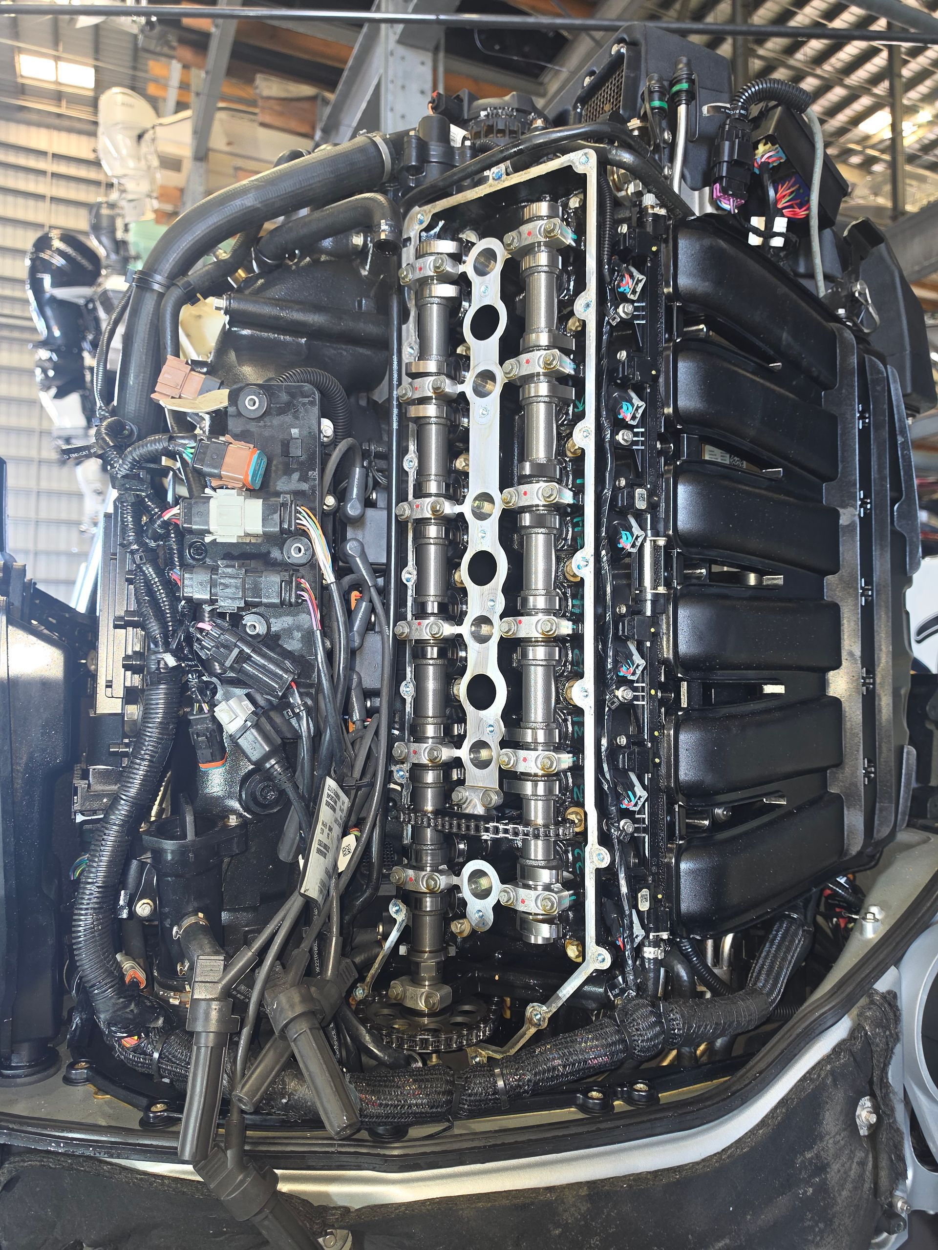Car engine bay with exposed black intake and silver valve cover during maintenance.