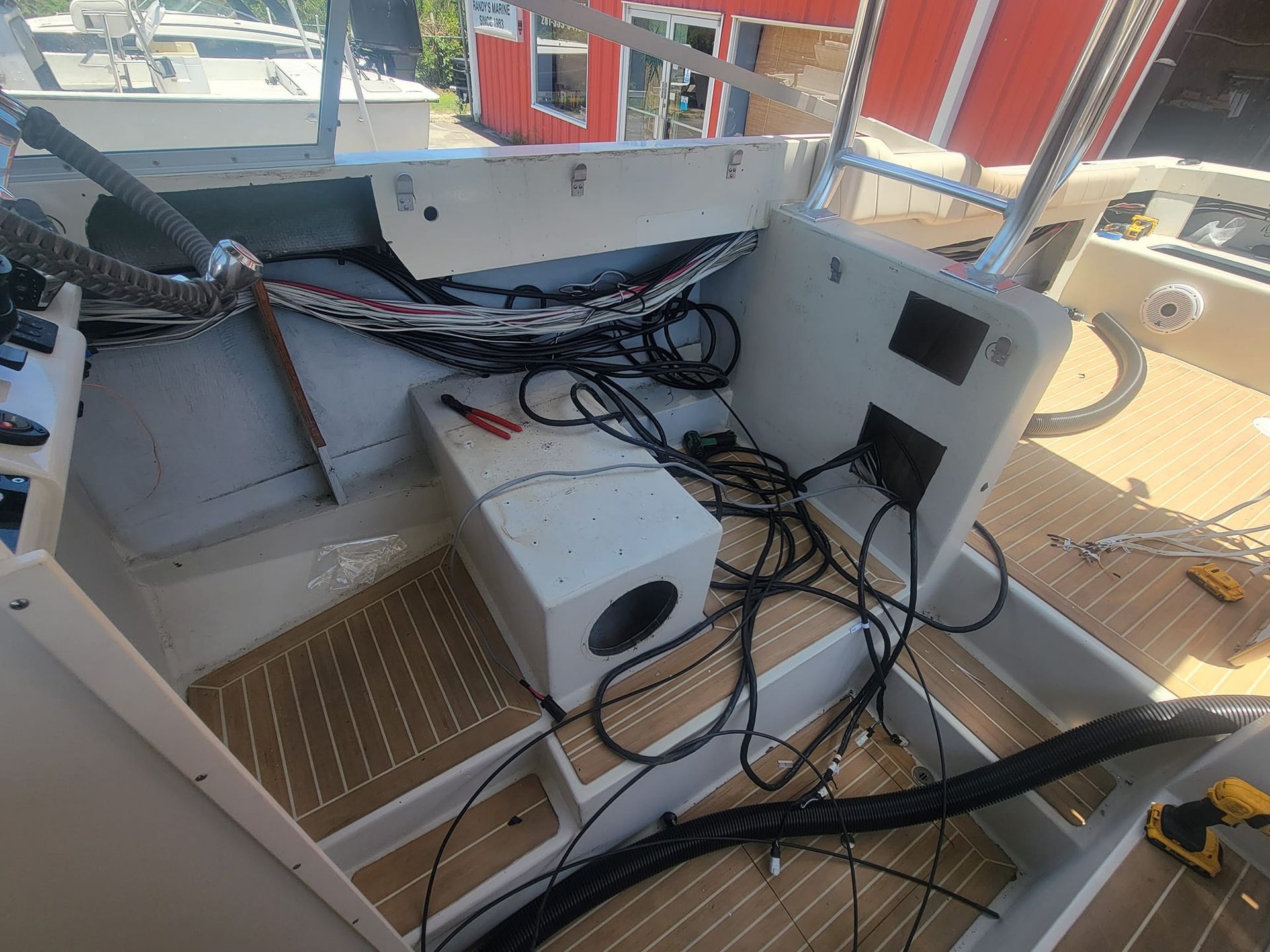Interior boat with exposed wiring and equipment. White cabinets, wood flooring, tools.