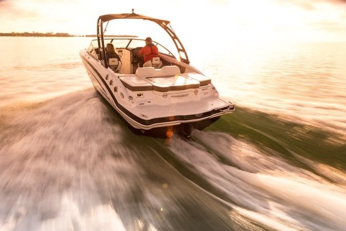 A white motorboat speeding on water, two people onboard, golden sunlight, ocean setting.