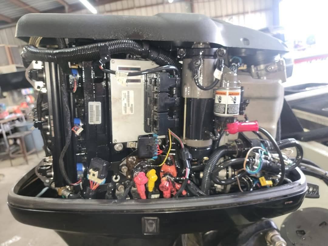 Close-up of a black boat engine with exposed wiring and fuel filter, likely for maintenance.