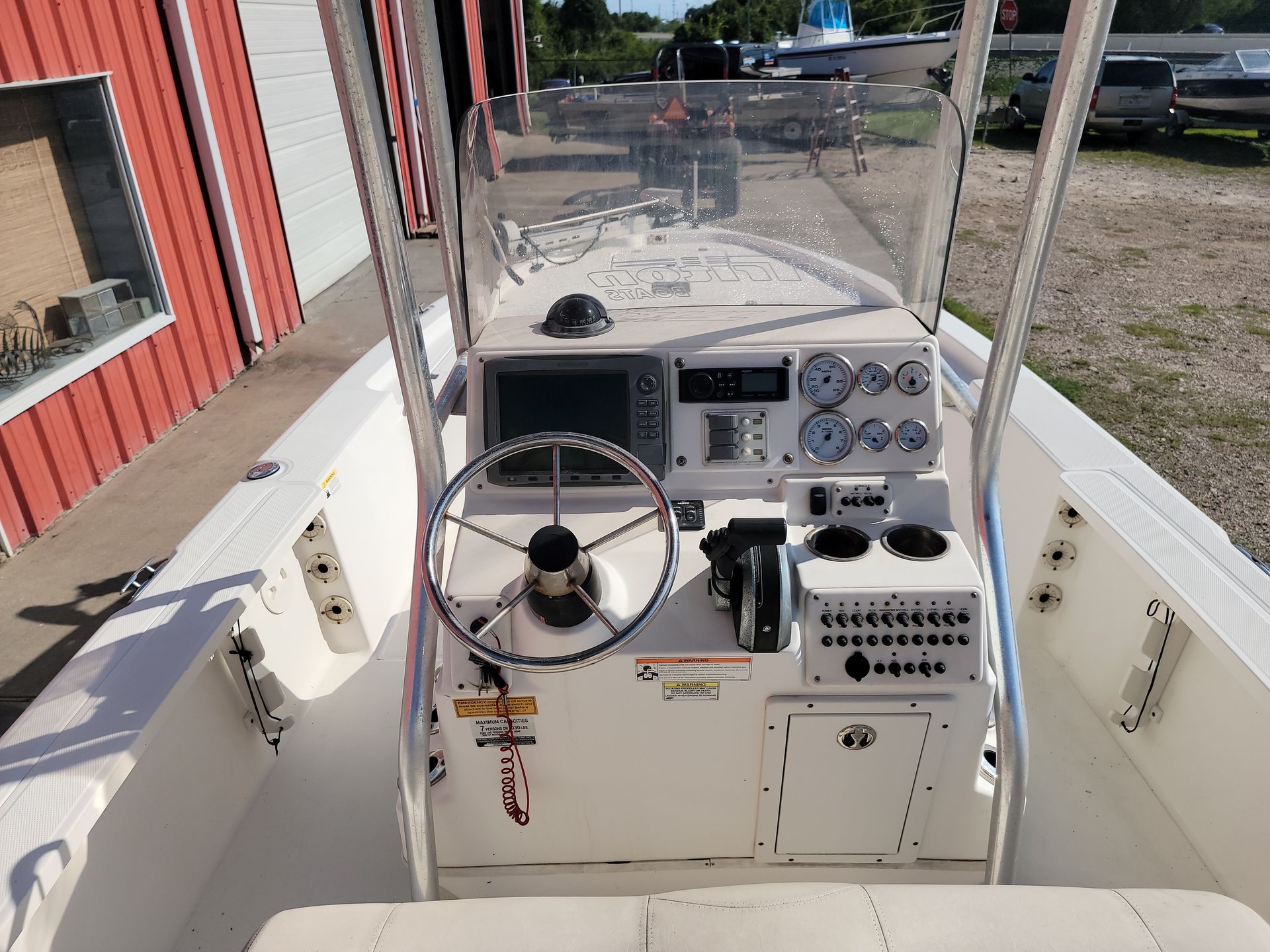 Boat's cockpit with steering wheel, gauges, navigation screen, and cup holders.