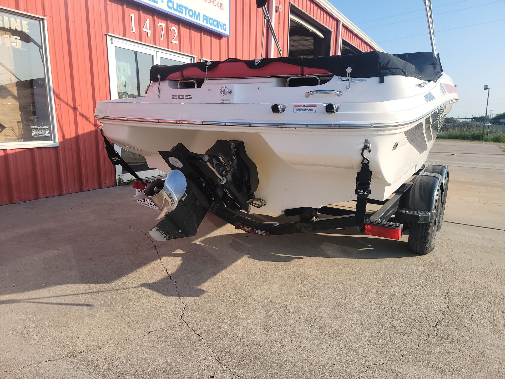 White boat on a trailer, parked in front of a building.
