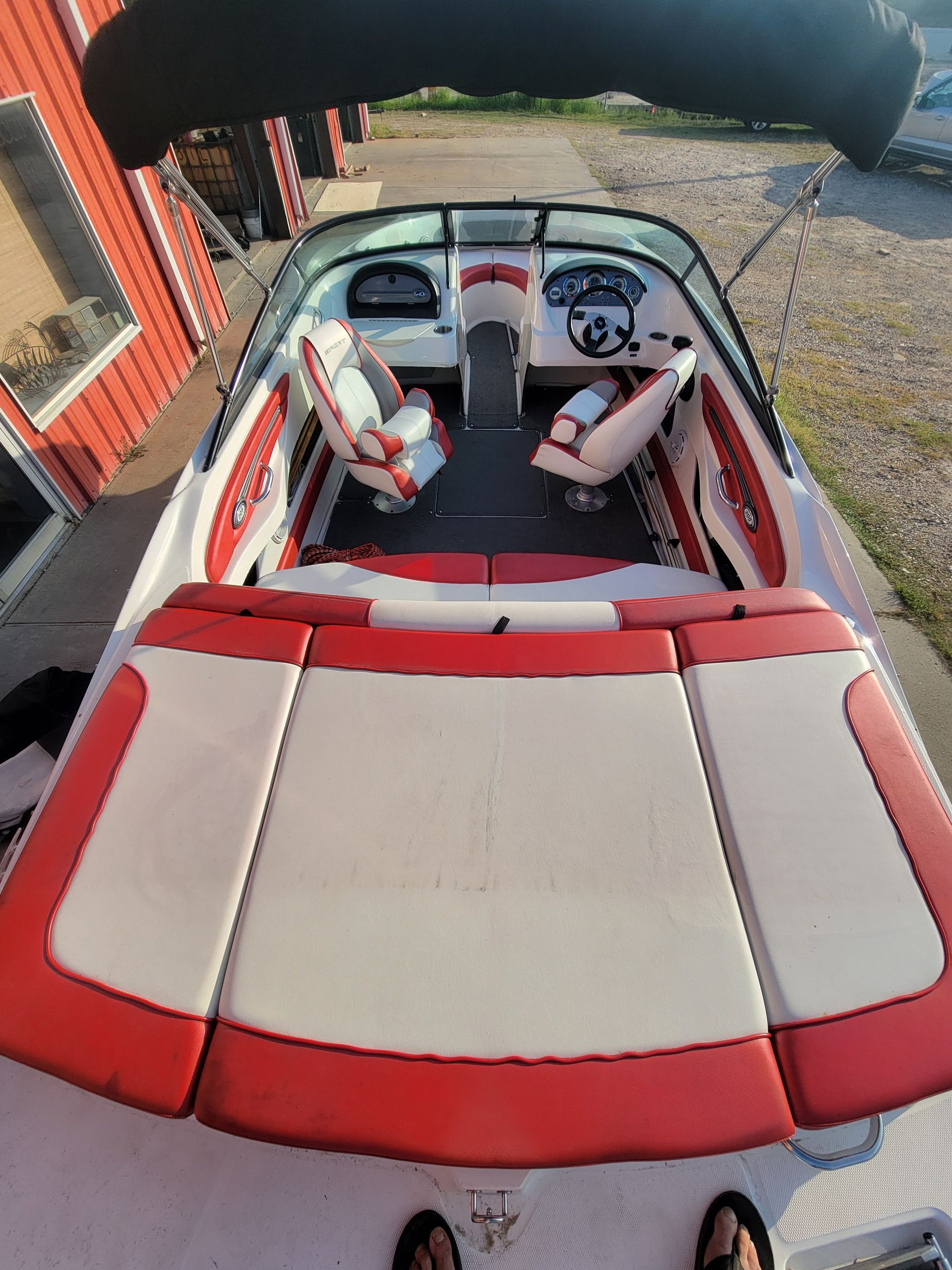 Red and white speedboat with black canopy on a sunny day.