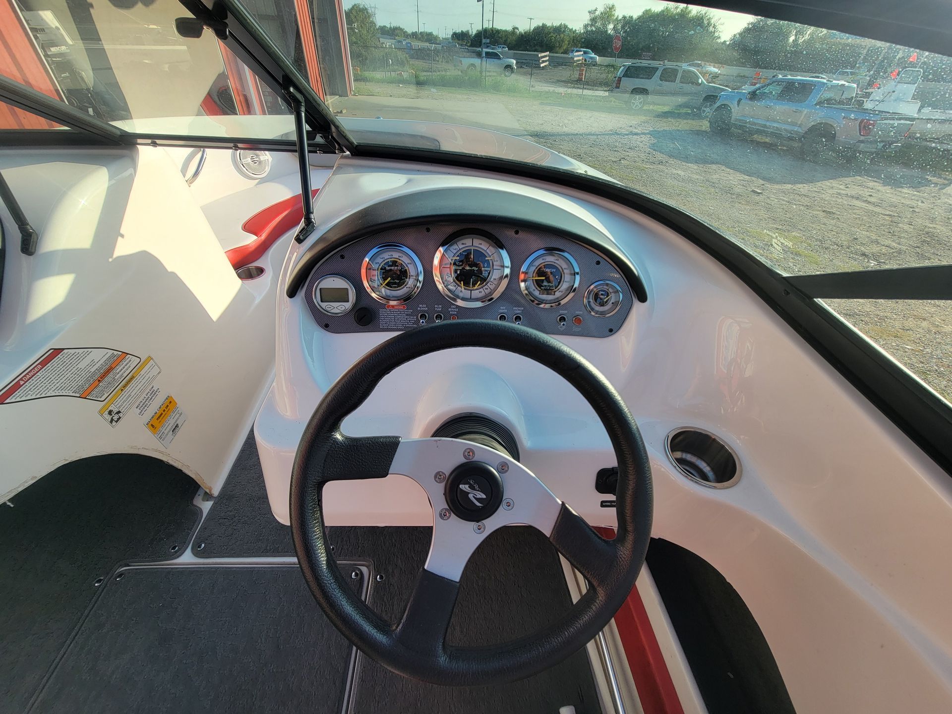 Boat dashboard with steering wheel and gauges.