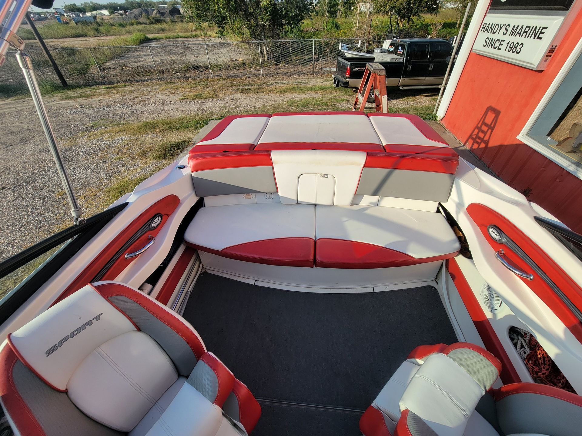 Interior of a white, red, and gray speedboat; seats, storage, and control panel visible.