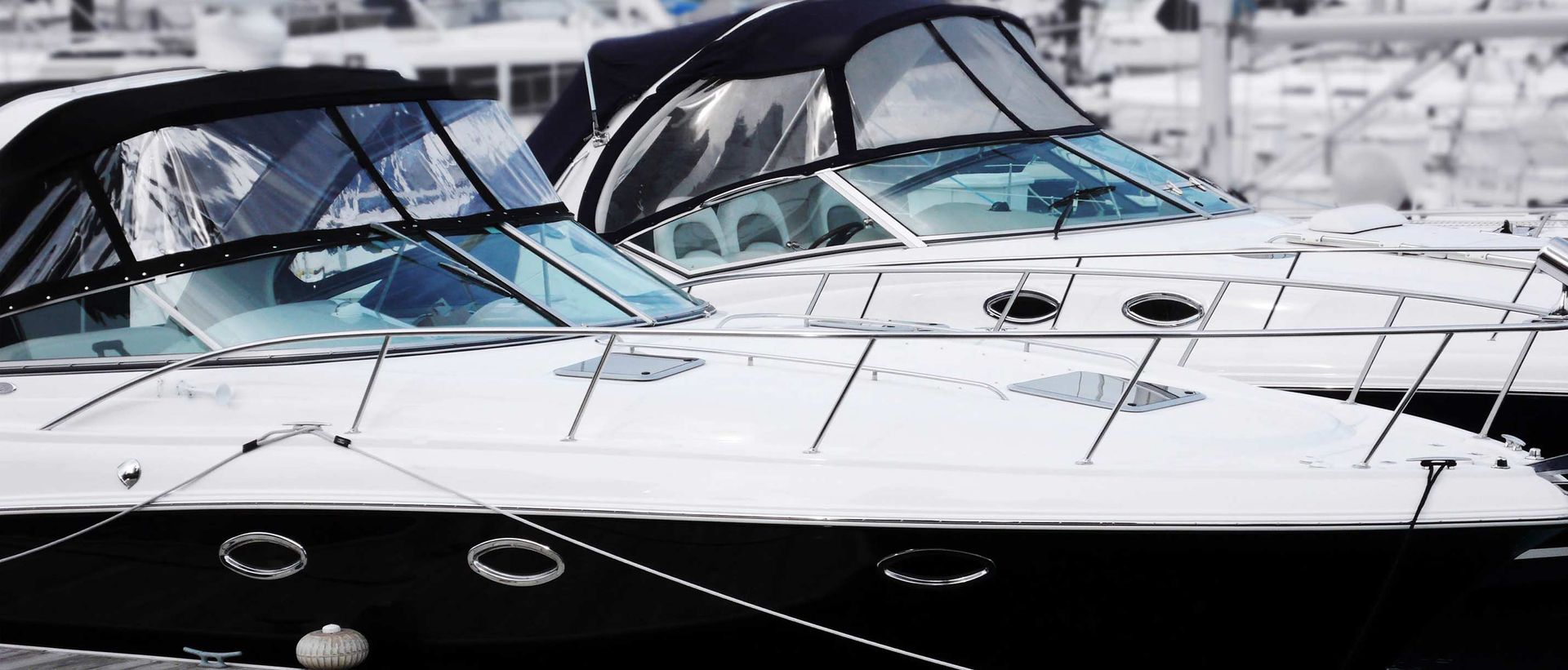 Boats docked at a marina, with white hulls, dark trim, and covered windshields.