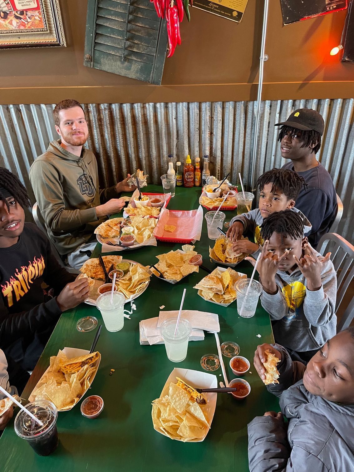 Group photo of 6 boys and men eating in a restaurant
