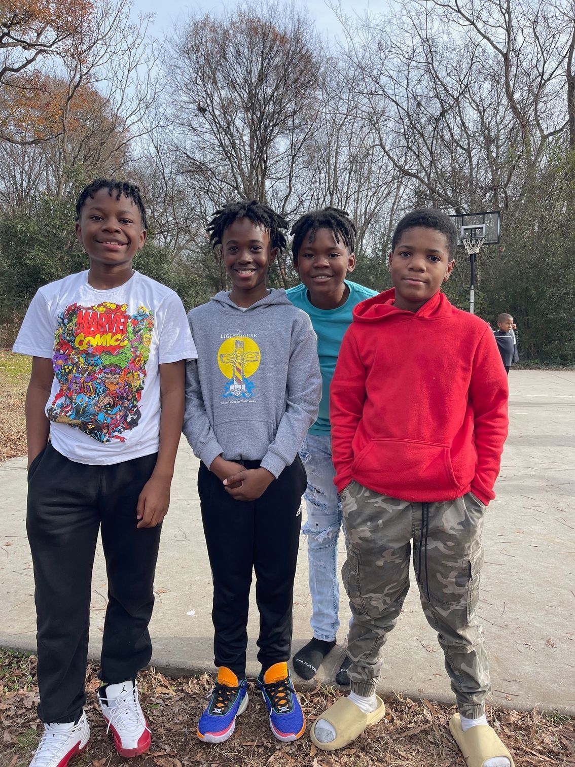 Four boys posing for a photo in an outdoor basketball court