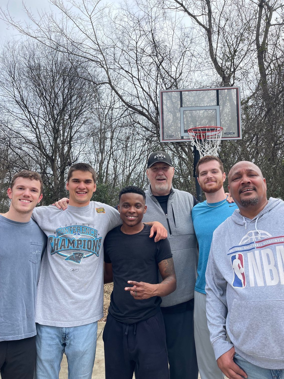 Group photo of six men in an open basketball court