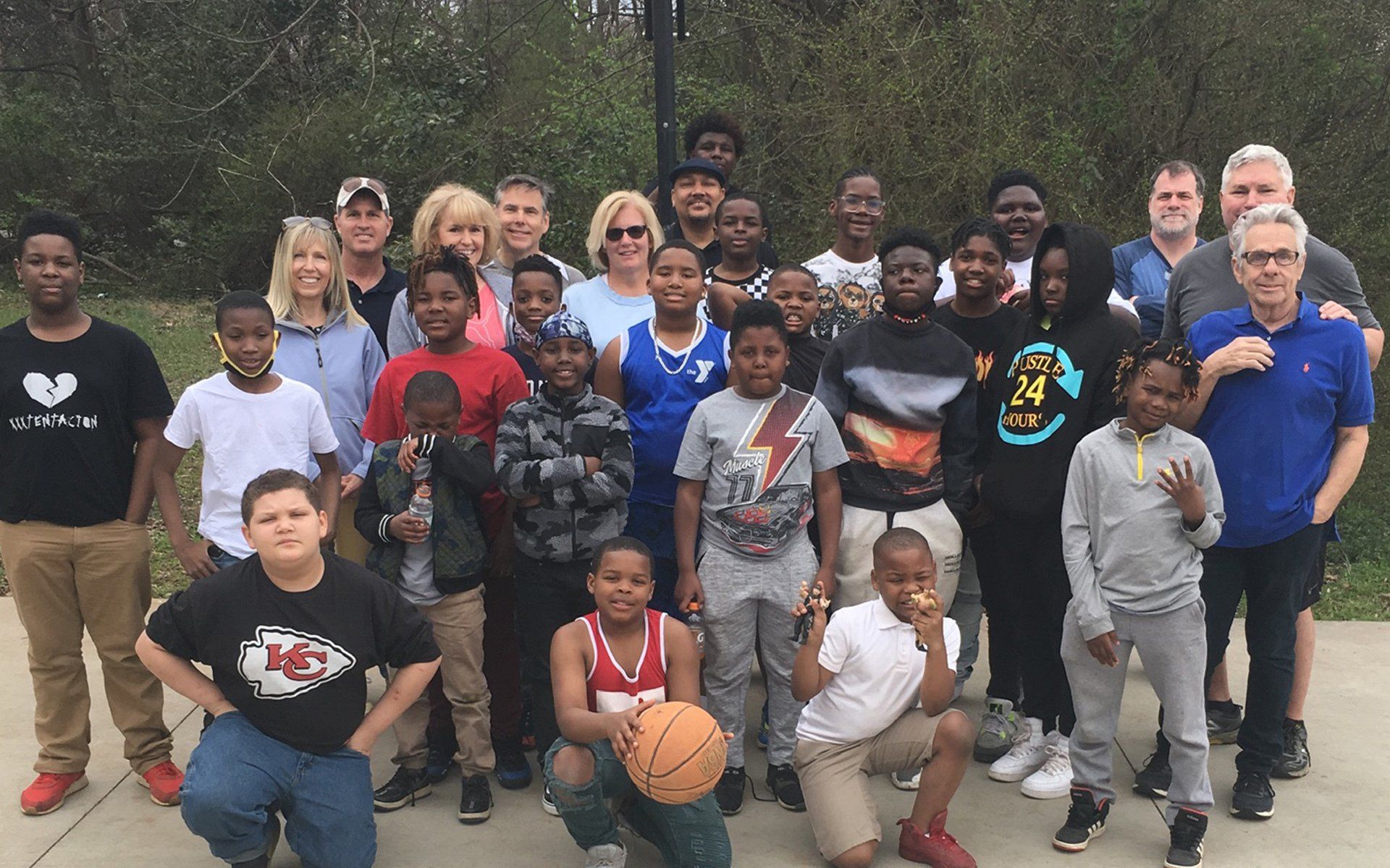 An outdoor group photo of several young boys, men, and women