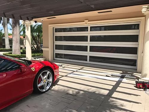 A red sports car is parked in front of a garage door.