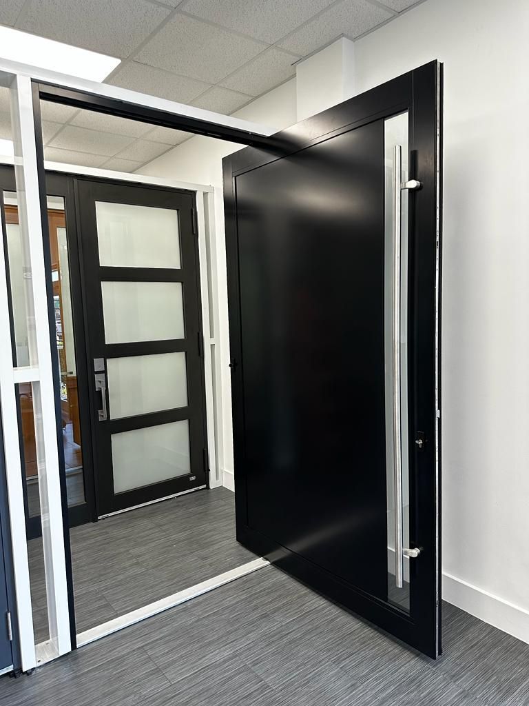 A black door with a stainless steel handle is open in a room.