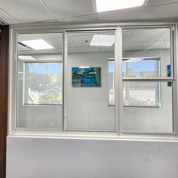 A room with a lot of windows and a painting on the wall.