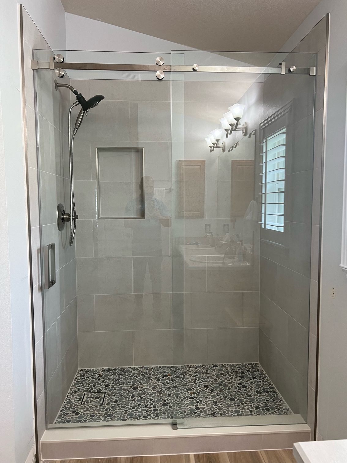 A bathroom with a sliding glass shower door and a shower head.