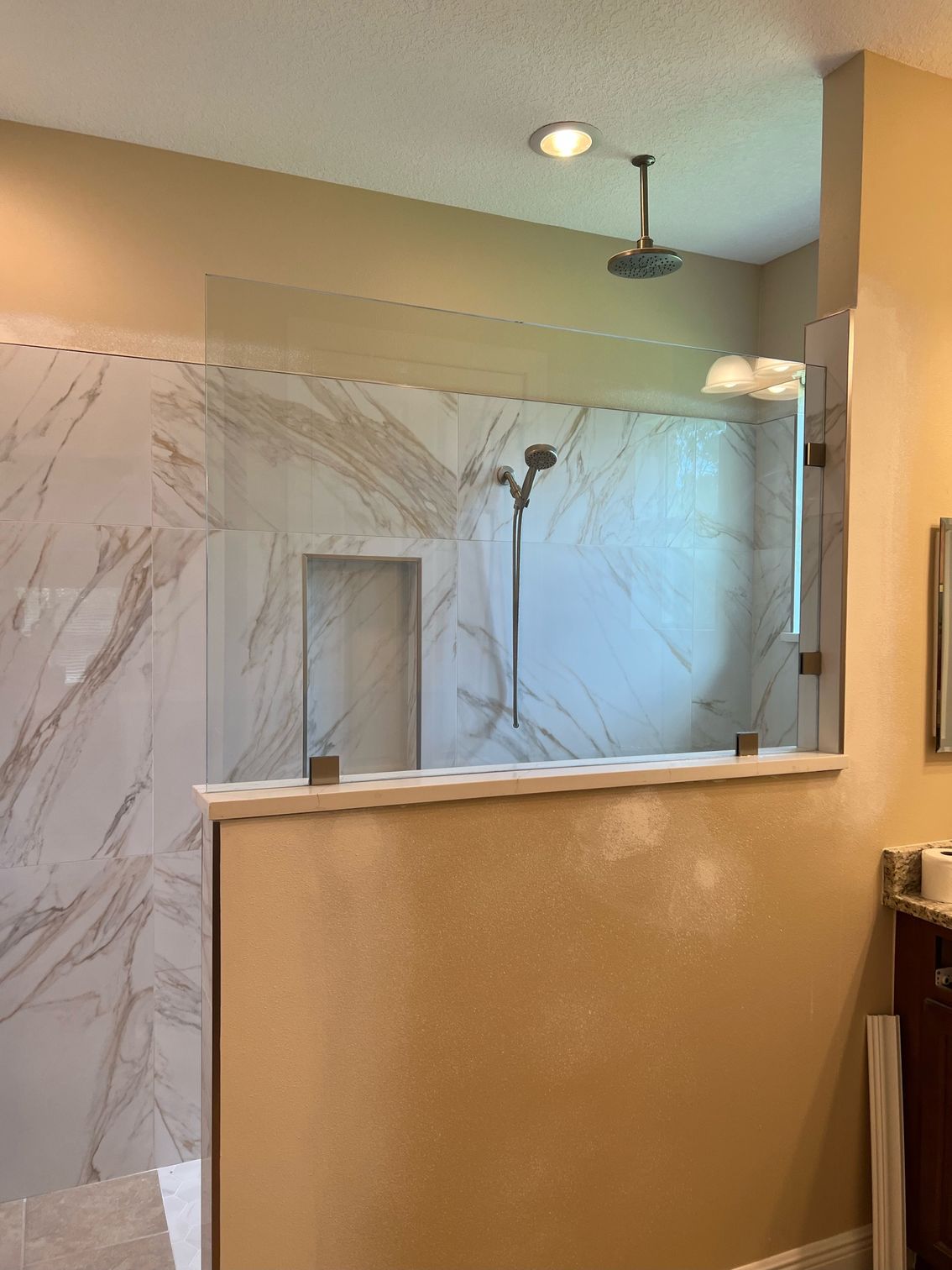A bathroom with a walk in shower and a shower head.