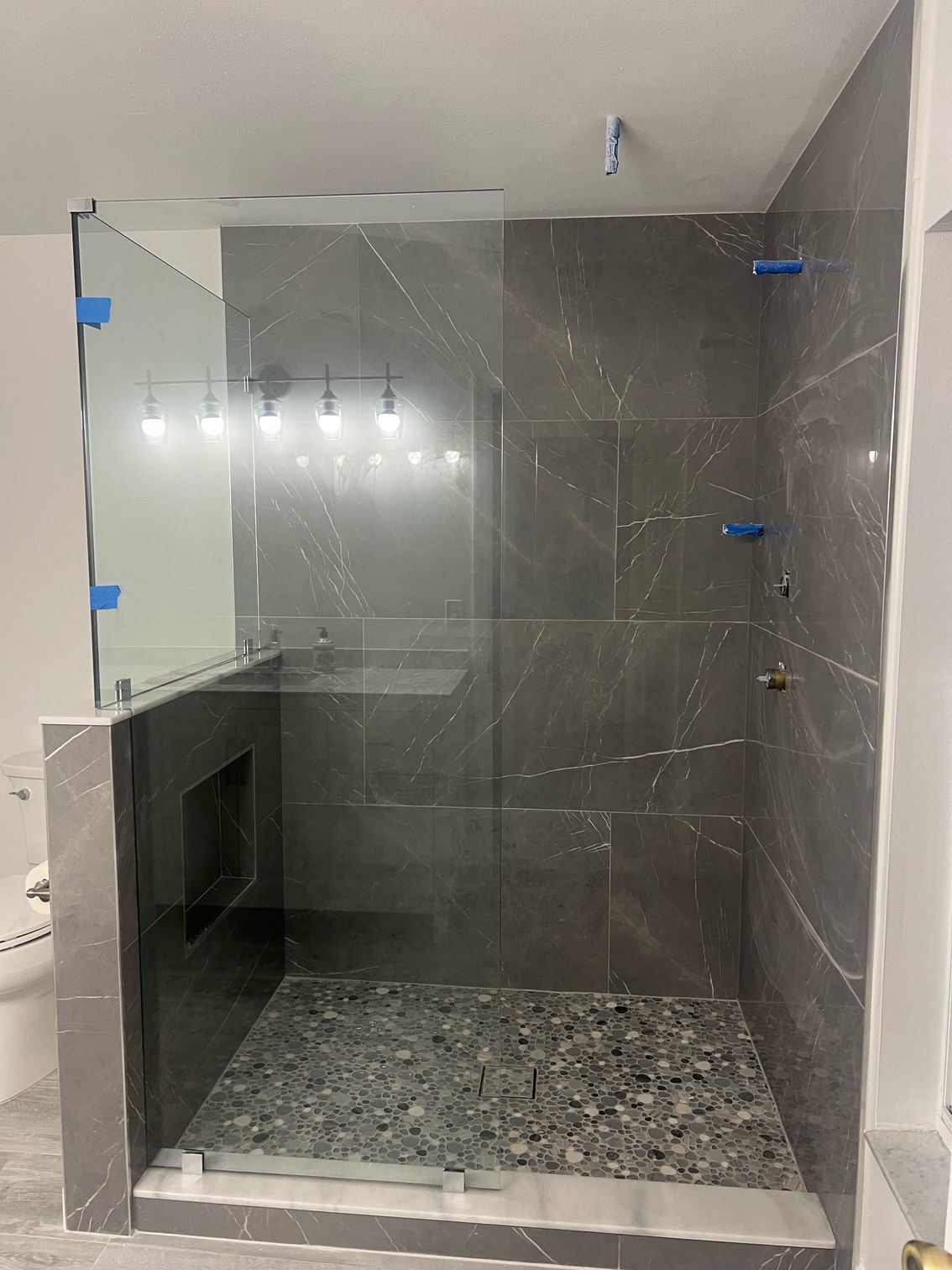 A bathroom with a walk in shower with a glass door.