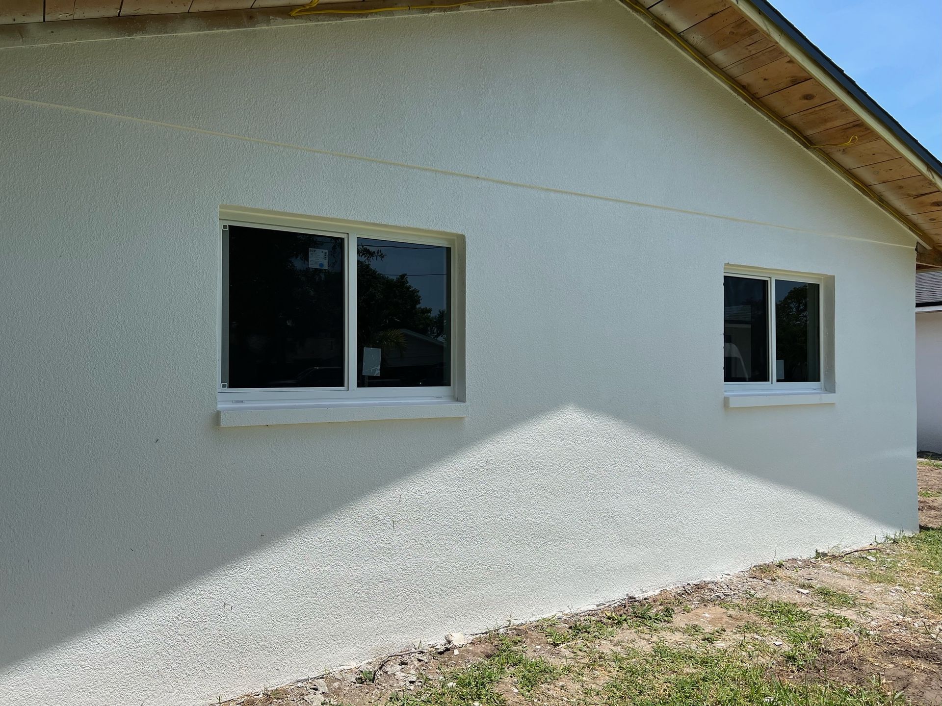 A white house with two windows on the side of it