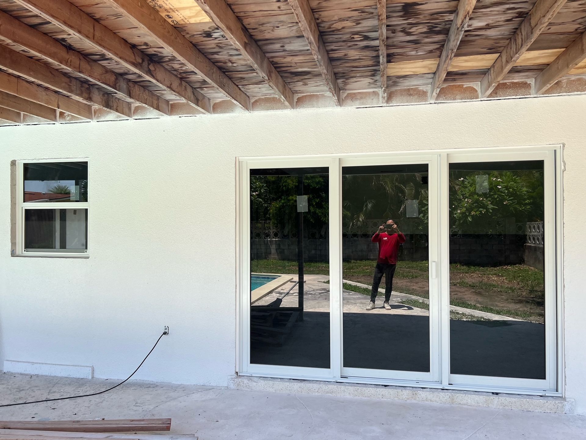 A man in a red shirt is standing in front of a sliding glass door
