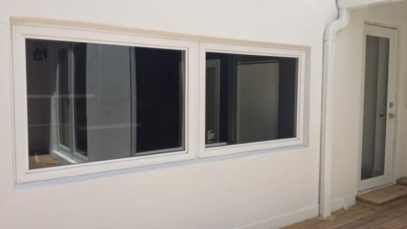 A white wall with two windows and a door in a room.