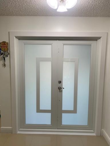 A pair of white doors with frosted glass in a hallway.