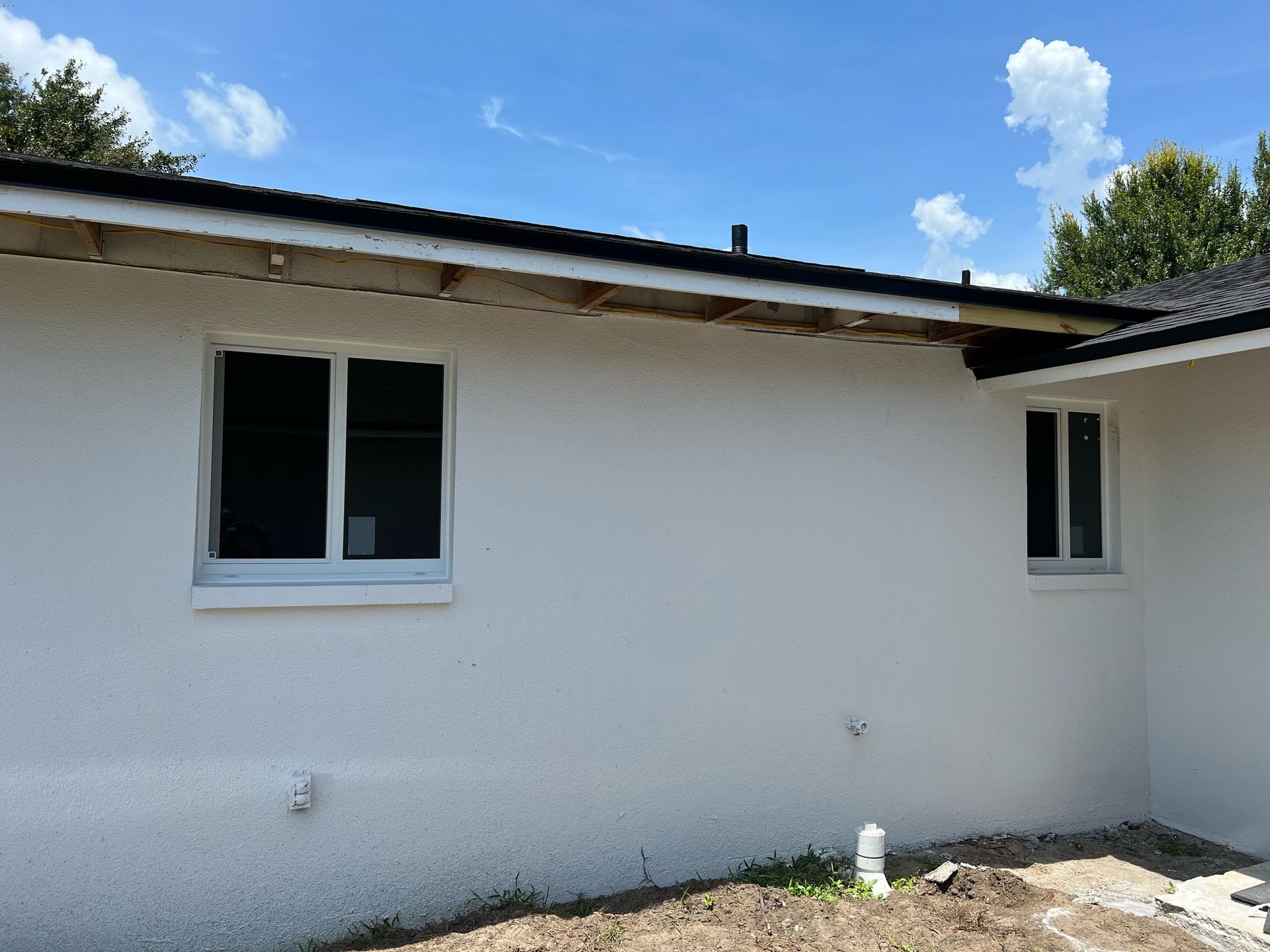 A white house with two windows and a blue sky in the background.