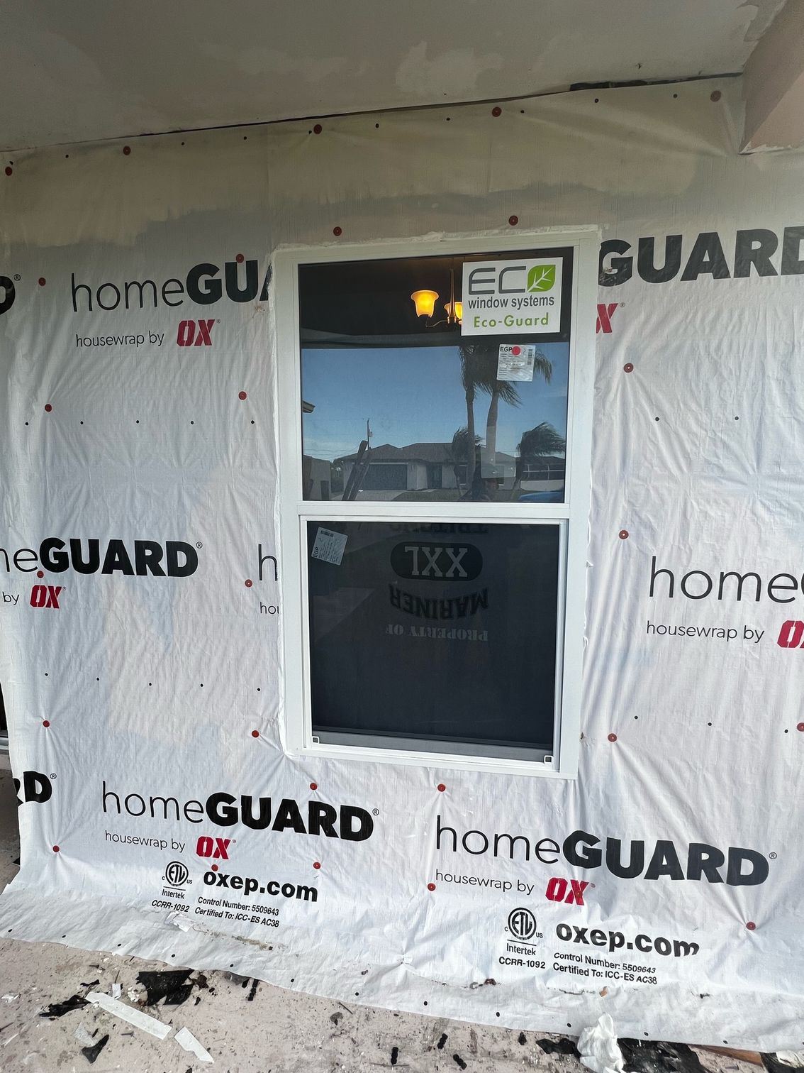 A window is being installed in a house that is covered in homeguard.