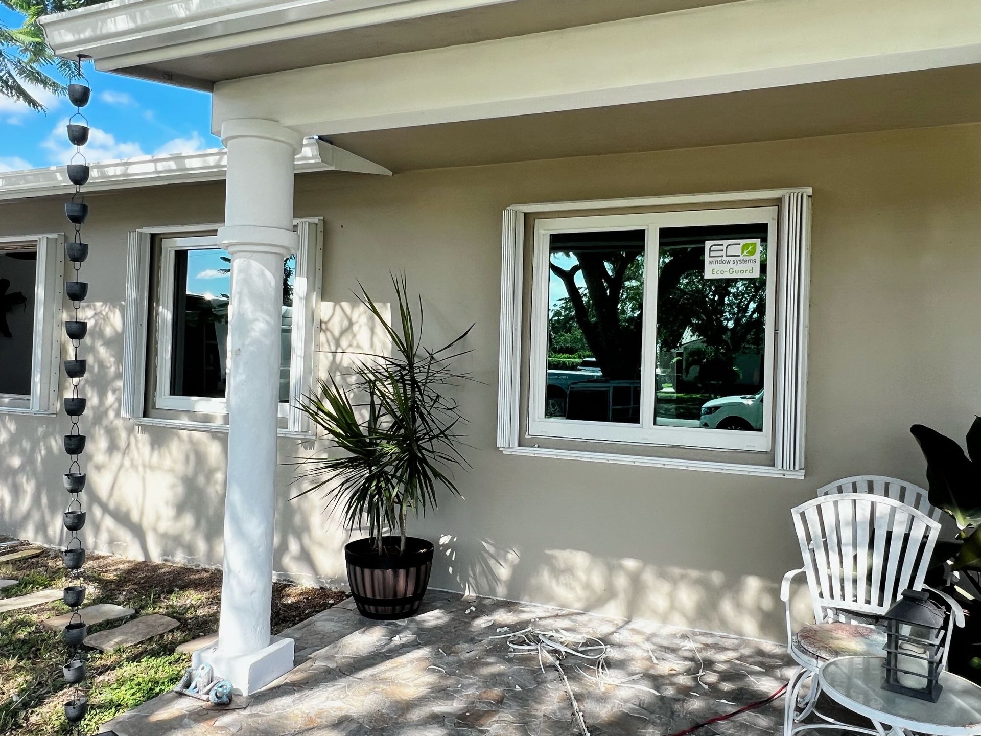 A house with a porch and a table and chairs in front of it.
