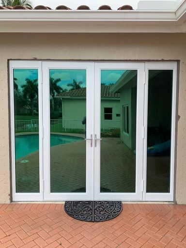 A pair of white sliding glass doors leading to a patio with a pool in the background.