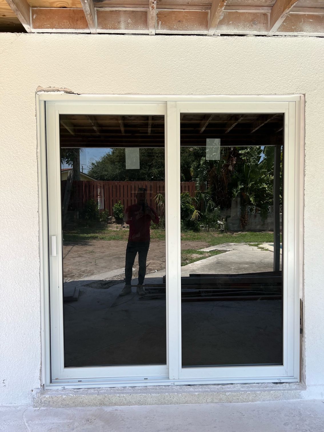 A man is standing in front of a sliding glass door.