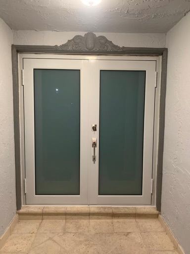 A white double door with frosted glass in a hallway.