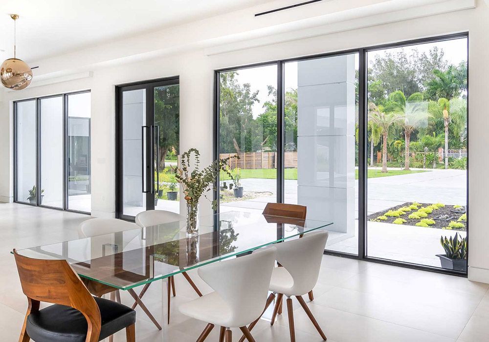 A dining room with a glass table and chairs and a lot of windows.